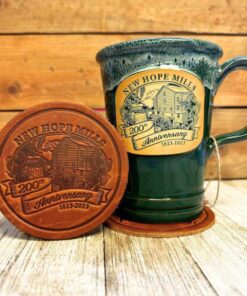 Photo of New Hope Mills 200th Anniversary Leather Coaster beside a green 200th Anniversary Mug