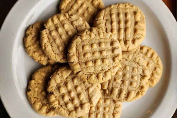 A plate of cookies using the New Hope Mills Protein Peanut Butter Cookie Recipe. Light tan cookies with fork imprints